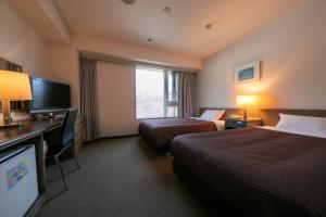 a hotel room with two beds and a flat screen tv at Hotel Beniya in Suwa