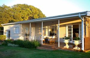 une maison blanche avec un porche avec une table et des chaises dans l'établissement Sneezewood Farm Bed&Breakfast and Self-Catering Cottage, à Dundee