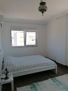 a white bedroom with a bed and a window at Private villa with pool and sauna in Altınkum