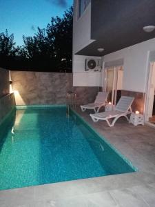 a swimming pool with two loungers next to a house at Private villa with pool and sauna in Altınkum