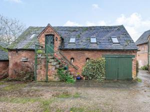 an old brick house with a green door and stairs at The Saddlery in Shirley