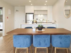 cocina con mesa de madera y sillas azules en Luxurious 2 bedroom apartment Free secure parking, en Auckland