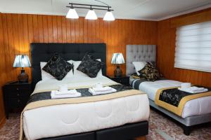 two beds in a room with wood paneled walls at Hotel Forjadores del Cabo de Hornos in Puerto Williams