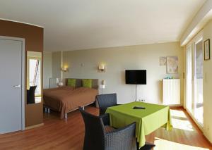 Habitación con cama, mesa verde y sillas. en Hotel Belvedere, en Heuvelland