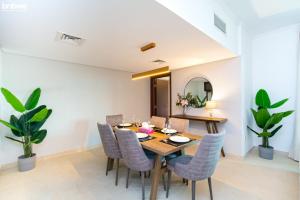 a dining room with a wooden table and chairs at bnbmehomes - 2 BR Stunning Lake Views in Al Turia - 205 in Dubai