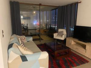 een woonkamer met een bank en een televisie bij Depto piso 6 frente al mar in Antofagasta