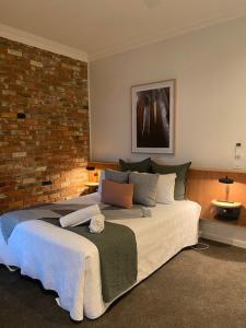 デイルスフォードにあるThe Royal Daylesford Hotelのレンガの壁のベッドルーム1室(大型ベッド1台付)