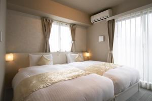 two beds in a hotel room with windows at Framboise KYOTO Hotel de charme in Kyoto