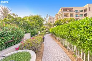 a path through a garden with flowers and a building at bnbmehomes - 2 BR Stunning Lake Views in Al Turia - 205 in Dubai