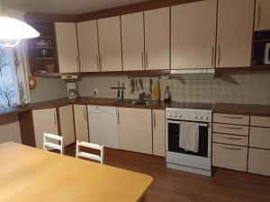 kuchnia z białymi szafkami, zlewem i stołem w obiekcie Saimaa home w mieście Lappeenranta