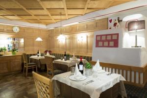 un restaurante con mesas, sillas y botellas de vino en Hotel Vajolet, en San Cassiano