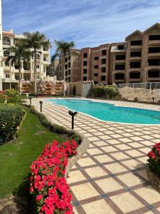 a resort with a swimming pool and some red flowers at Apartman Andalusie in Hurghada