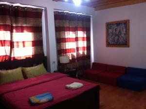 a bedroom with a red bed and a couch at Blueberry Rooms in Qasrîne