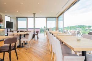 um restaurante com mesas e cadeiras de madeira e janelas em Bihotel em Comerzo