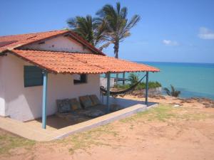 een huis op het strand met een bank onder een parasol bij Casa do amor in Pipa