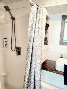 uma casa de banho com uma cortina de chuveiro e um lavatório em Charming Tiny Home with private deck and bbq em Apple Valley