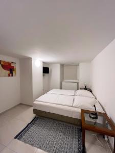 a white bedroom with a bed and a glass table at Pension Thomas Rooms in Berlin