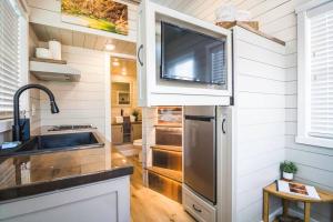 uma cozinha com um lavatório e uma televisão na parede em Delightful tiny home conveniently located em Apple Valley