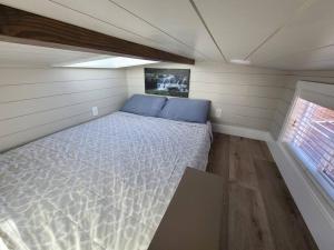 Cama en habitación pequeña con ventana en Delightful tiny home conveniently located en Apple Valley