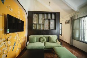 uma sala de estar com um sofá e uma televisão em Impresso Home & Cafe Hanoi em Hanói