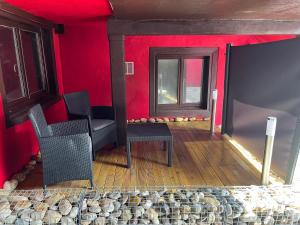 een kamer met een rode muur, 2 stoelen en een raam bij L’Alsacienne room et spa in Lautenbach