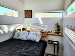 um pequeno quarto com uma cama e 2 janelas em Designer Modern Tiny Home w All of The Amenities em Apple Valley