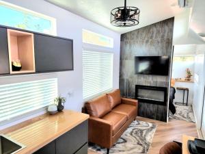 a living room with a brown leather couch and a fireplace at Designer Modern Tiny Home w All of The Amenities in Apple Valley