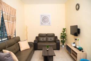 a living room with a couch and a tv at Adorable 3-bedroom home with Wi-Fi, Netflix and BBQ grill in Rembau