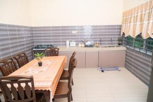 uma cozinha com uma mesa e uma mesa e cadeiras em Adorable 3-bedroom home with Wi-Fi, Netflix and BBQ grill em Rembau