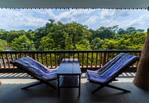 2 Stühle und ein Tisch auf einem Balkon mit Bäumen in der Unterkunft Chitwan Gaida Lodge Pvt. Ltd. in Sauraha