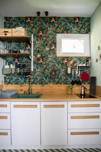 cocina con armarios blancos y papel pintado con motivos florales en Kikapcsol-LAK, en Bogács