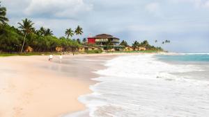 two people walking on the beach near the ocean at The garden gate resort & apartments no 3 in Negombo