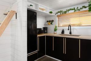 a kitchen with black cabinets and a sink at Zion Tiny Home, Private Hot Tub, Near Trails in Apple Valley