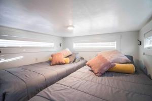 two beds in a small room with two windows at New modern & relaxing Tiny House w deck near ZION in Apple Valley