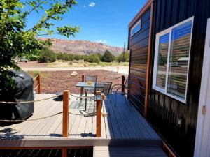a wooden deck with a table and chairs on a house at New modern & relaxing Tiny House w deck near ZION in Apple Valley