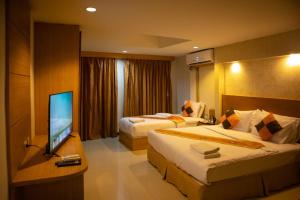 a hotel room with two beds and a flat screen tv at The ESSE Hotel Pattaya in Pattaya South