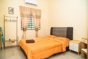 um quarto com uma cama com uma colcha laranja e uma janela em Adorable 3-bedroom home with Wi-Fi, Netflix and BBQ grill em Rembau