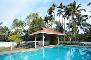 a swimming pool with a gazebo and palm trees at Bamboo Lagoon Backwater Front Resort in Alleppey