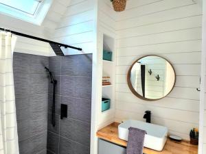 uma casa de banho com um chuveiro, um lavatório e um espelho. em Romantic Tiny home with private deck em Apple Valley