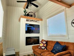 Romantic Tiny home with private deck في Apple Valley: غرفة معيشة مع أريكة وتلفزيون بشاشة مسطحة
