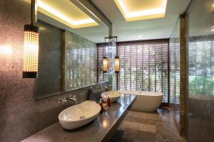 La salle de bains est pourvue d'un lavabo, d'une baignoire et d'un miroir. dans l'établissement Adiwana Bisma, à Ubud
