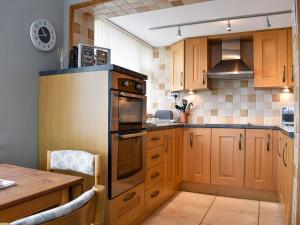 cocina con armarios de madera y horno con fogones en Dolphin Cottage, en Grange-over-Sands