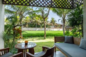 un patio con sofá, mesa y árboles en Adiwana Bisma, en Ubud