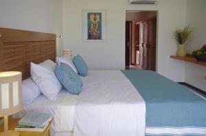 a bedroom with a large white bed with blue pillows at PAUSA Hotel in Fortim