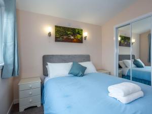 a bedroom with a blue bed and a mirror at Kilninver - Uk31537 in Kirkhill