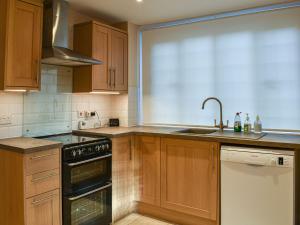 a kitchen with wooden cabinets and a sink and a dishwasher at The Lodge in Coton