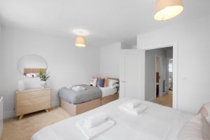 a white bedroom with a bed and a mirror at Design-Led Luxurious Townhouse Prime Location W/ Parking in Reading