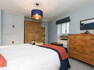 a bedroom with a white bed and a wooden dresser at Crescent Cottage in Askham