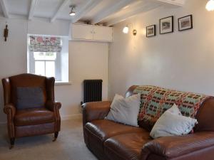 sala de estar con sofá de cuero y silla en Caer Pwll, en Morfa Nefyn