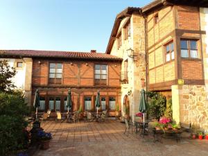 a building with a patio with tables and chairs and umbrellas at Señorio De Altamira - Adults Only in Santillana del Mar